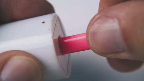 man sharpens pink pencil with sharpener on light background