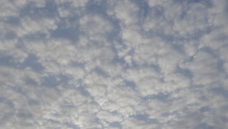 Perfectly-fluffy-white-grey-clouds-lightly-illuminated-by-sun,-timelapse-across-sky