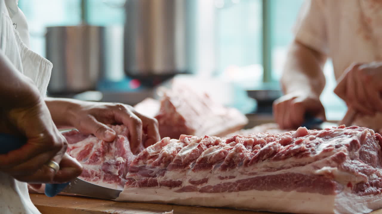 Two butchers preparing meat at a butcher's shop, mid section