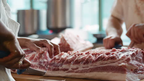 two butchers preparing meat at a butcher's shop, mid section