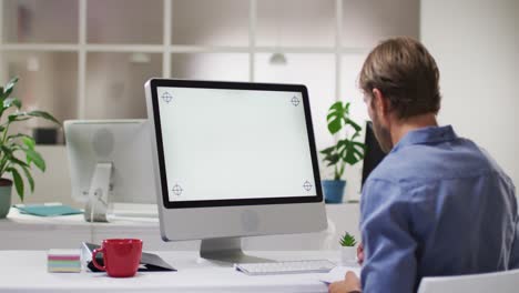 hombre de negocios caucásico teniendo una reunión de videollamadas usando una computadora de escritorio en el escritorio de la oficina