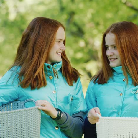 two young female red-haired farmers come with baskets in the apple garden 1