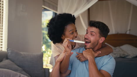 Una-Pareja-Emocionada-En-El-Dormitorio-De-Casa-Celebrando-El-Resultado-Positivo-De-La-Prueba-De-Embarazo