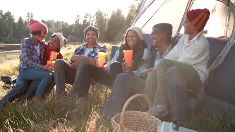 Multi-generation-family-on-camping-trip-sit-outside-tent