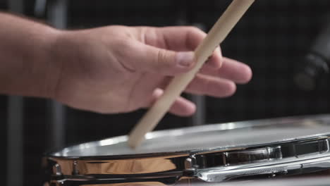 musician hand striking beat with stick to drumhead
