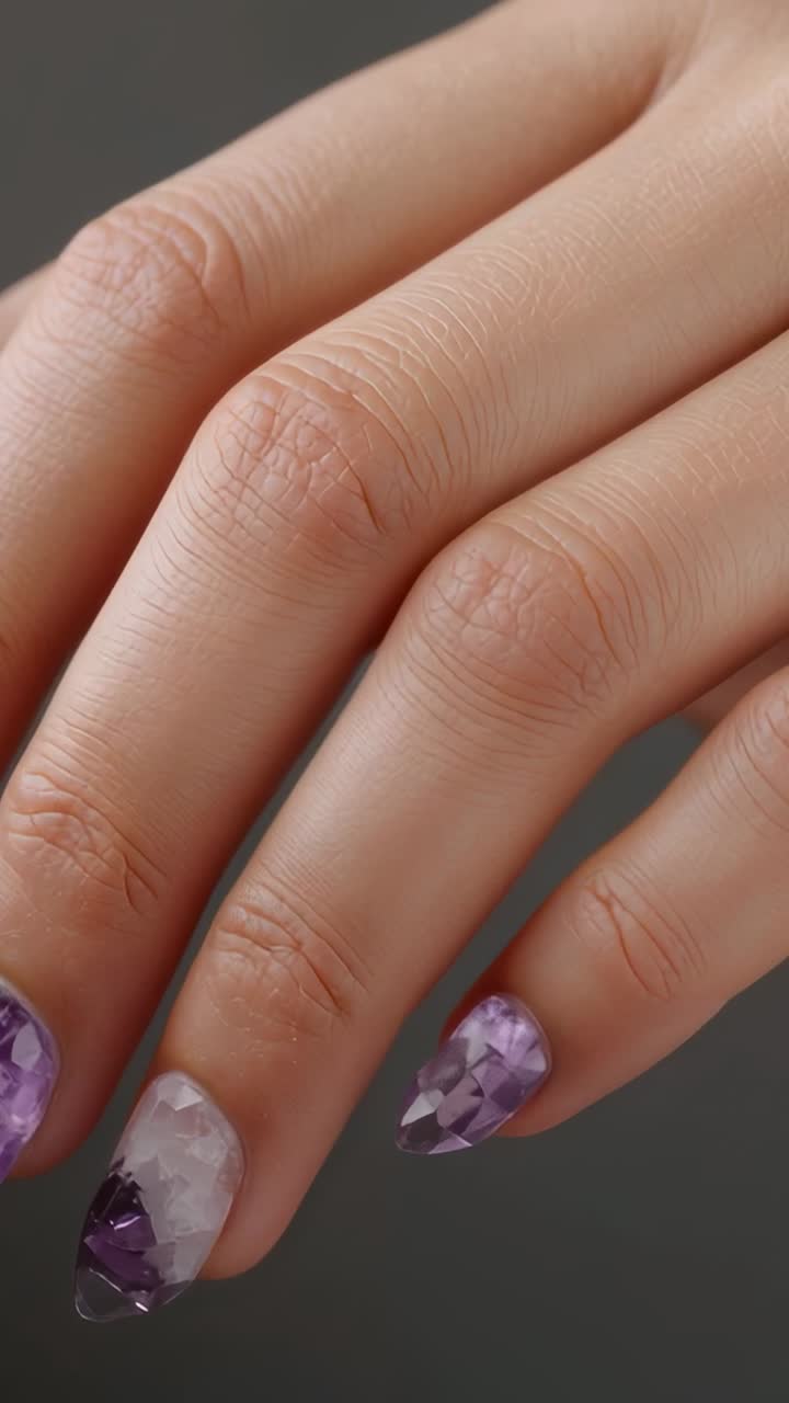 Vertical video: Turning right hand showing faceted purple nails in studio, light catching facets