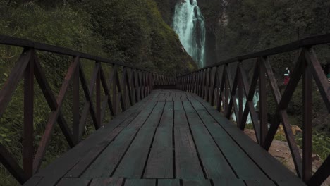 low angle view along empty wooden bridge leading to peguche waterfalls in otavalo
