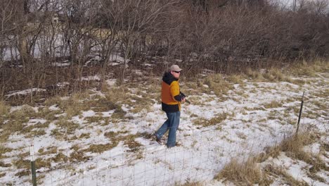 Hunter-holding-sniper-rifle-and-looking-for-targets,-early-spring-landscape