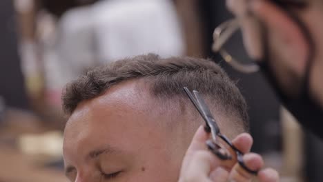 corte de pelo de barbero usando tijeras, el barbero hace el corte de pelo para el novio cliente en la barbería