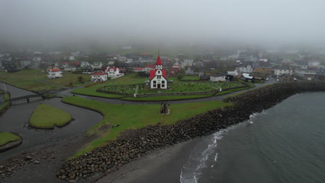 sandavagur village, vagar island: aerial view traveling out to the church and the village from the coast