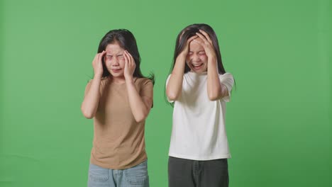 young asian women victims of violence with bruise on bodies having nervous breakdown and screaming in the green screen background studio