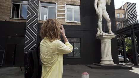 woman taking picture of david statue in a city