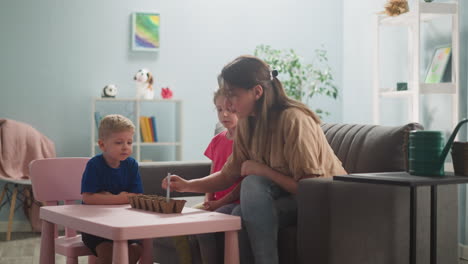 una mujer joven con niños pequeños en la habitación está plantando plantas