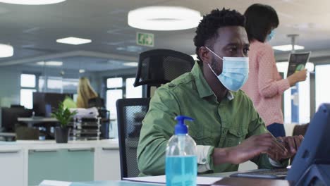 man wearing face mask using computer at office