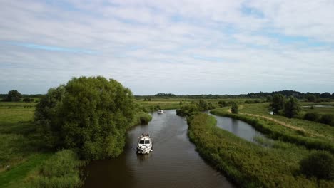 Eine-Wegfliegende-Luftdrohnenaufnahme-Eines-Bootes,-Das-Entlang-Des-Flusses-Yare-Und-Der-Ländlichen-Umgebung-Der-Norfolk-Broads-Fährt