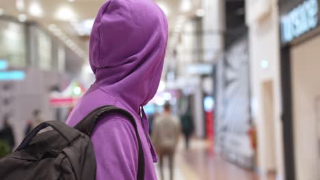 young hooded modern indian man pensive looking in a shopping mall