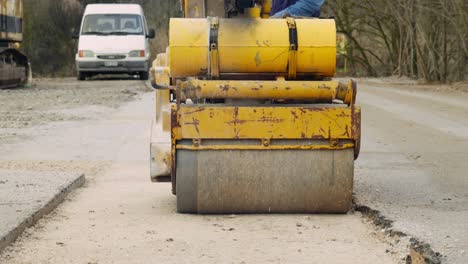 middle age worker male operate hand operated mini road roller compactor ground new road slow motion