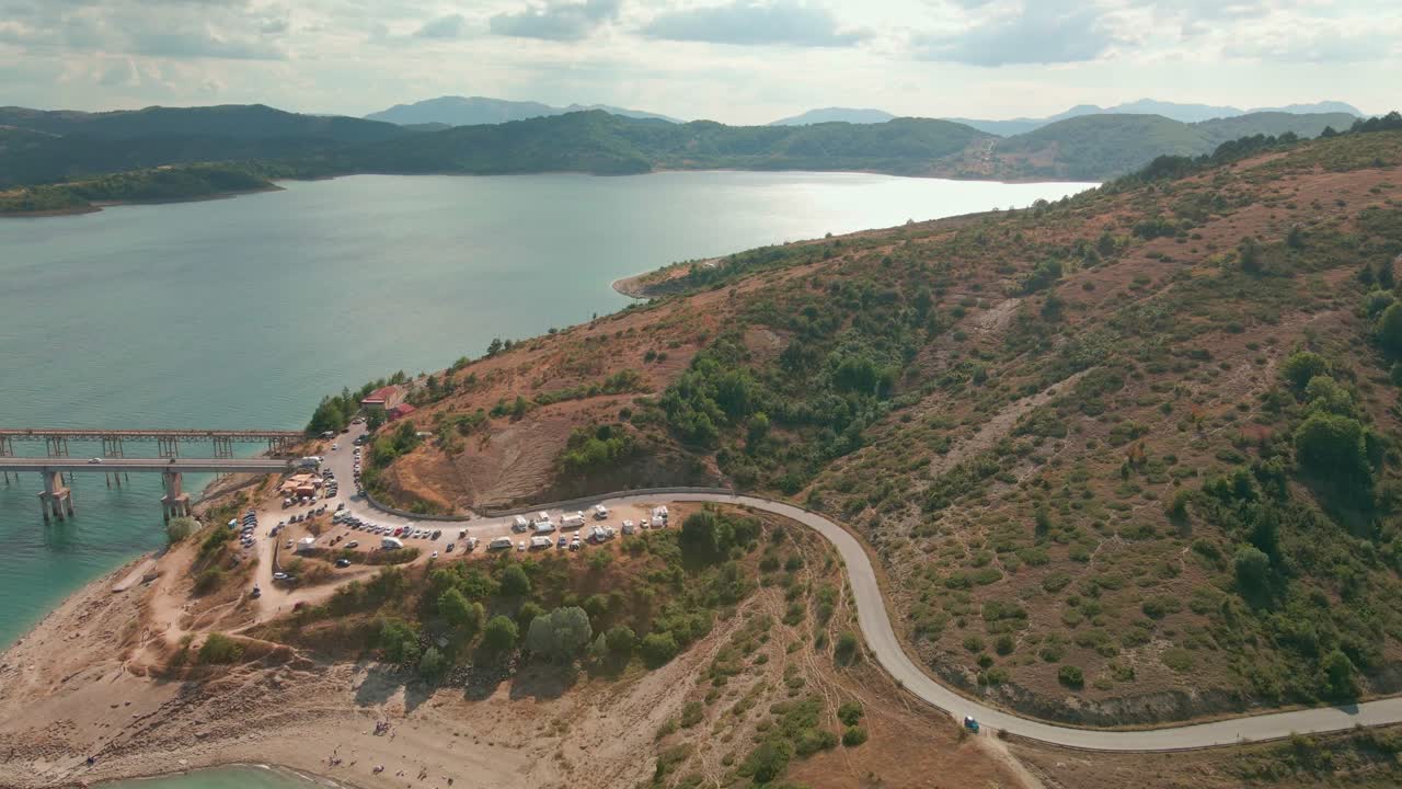 coches aparcados junto a la carretera al lado de una montaña en el lago de campotosto, italia - toma aérea