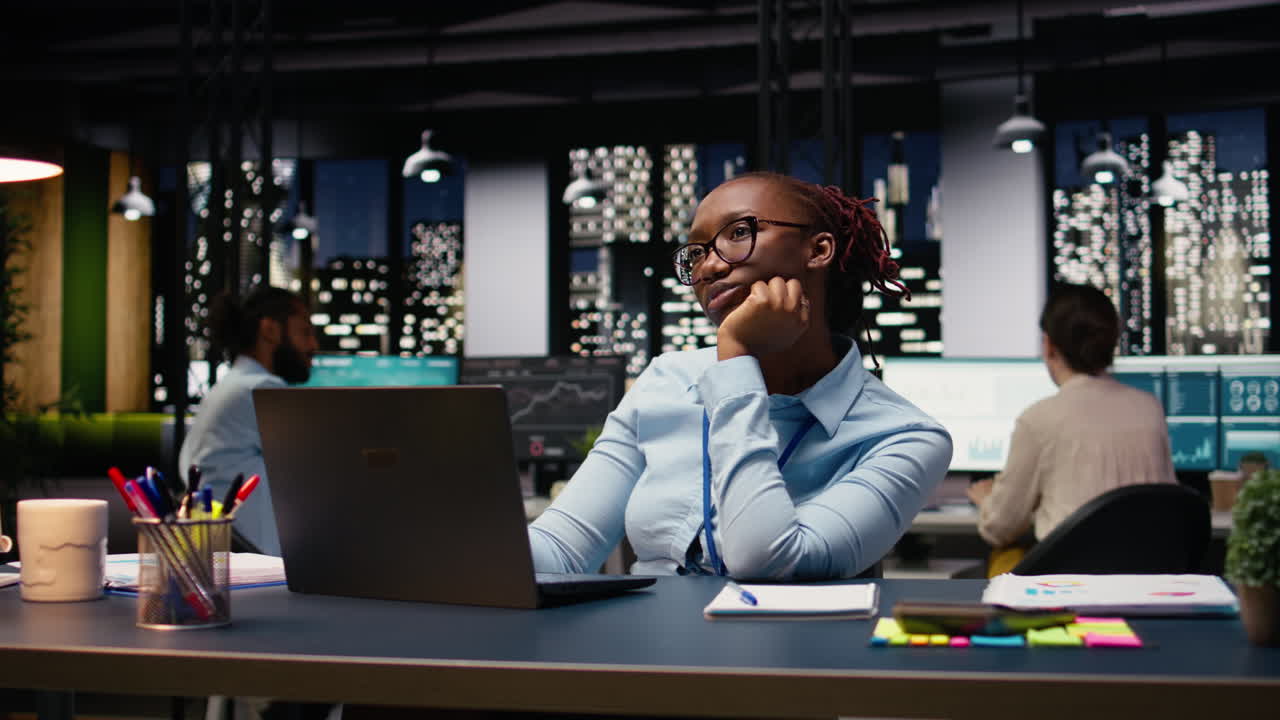 Black manager thinking about new ideas while reviewing notes on laptop