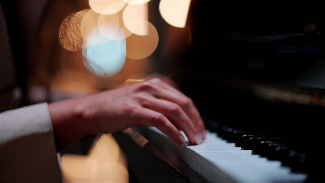 Close up of a woman's hands playing the piano with blurry lights on the background