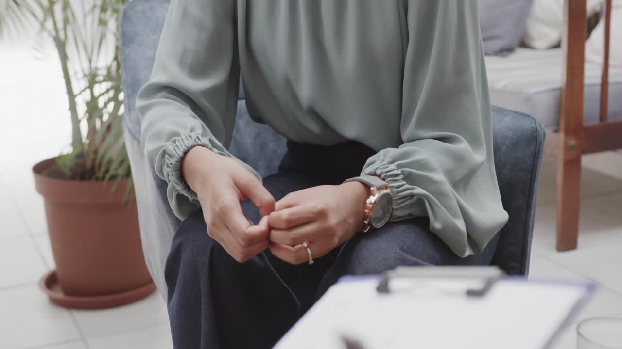 Midsection of diverse male therapist and female patient talking in therapy session, slow motion