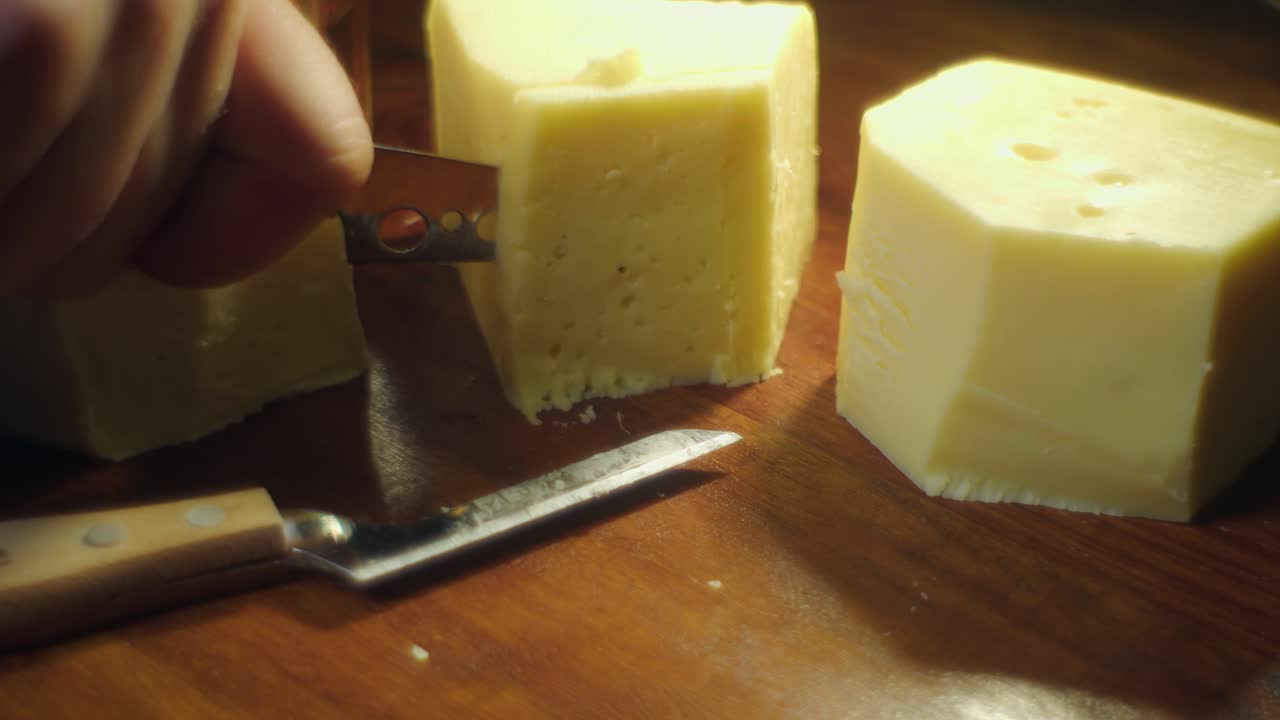 primer plano de enfoque suave: queso brillante en la tabla de cortar cortado con cuchillo