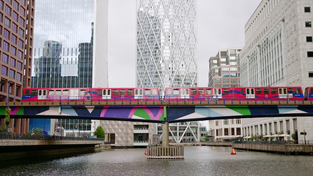 Street scape of the Canary Wharf district, water channels with train moving on a bridge, skyscrapers around in London, United Kingdom