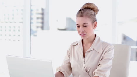 Smiling-blonde-businesswoman-using-laptop