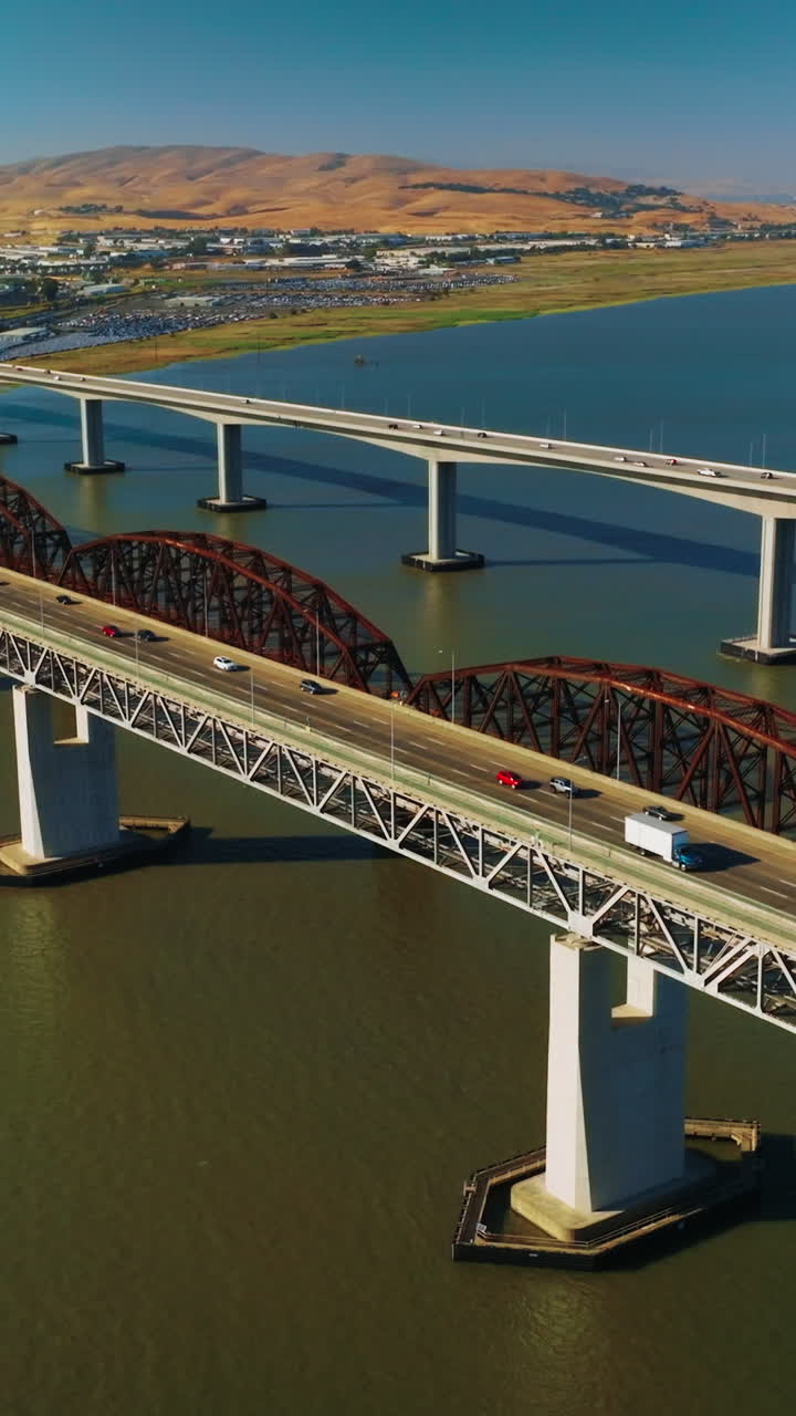 Bridges connecting Martinez to Benicia with transport moving by. Beautiful panorama of the strait and rocky landscape of Martinez, California on sunny daytime. Vertical video