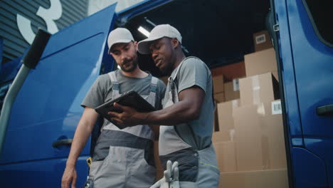 delivery men managing packages with a tablet from van