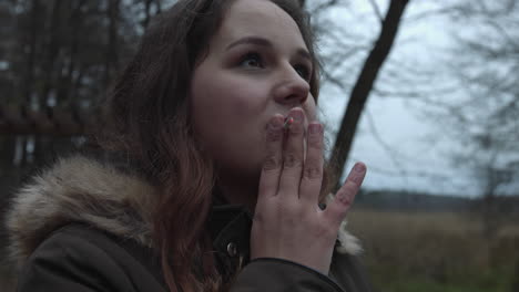 woman with long wavy hair siting on a park smoking - close up shot