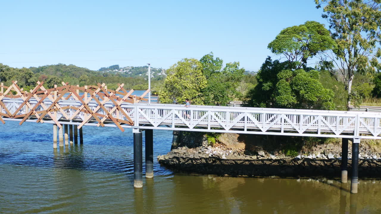 강 위의 다리 판자 위를 달리는 남자 선수의 무인 항공기 보기, 4k