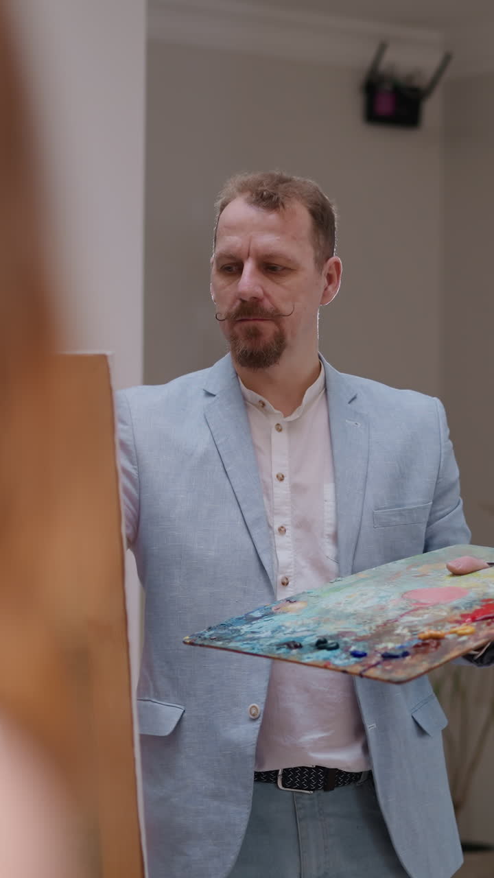 художник с пронзительными глазами рисует жизнь в студии. элегантный художник создает портрет женщины, работая с моделью в мастерской. творческое занятие и хобби