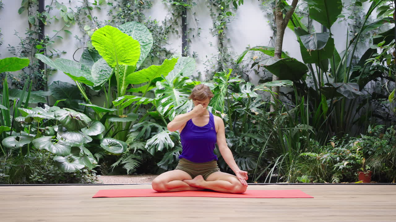 Woman Practicing Alternate Nostril Breathing Yoga in a Serene Plant-Filled Studio