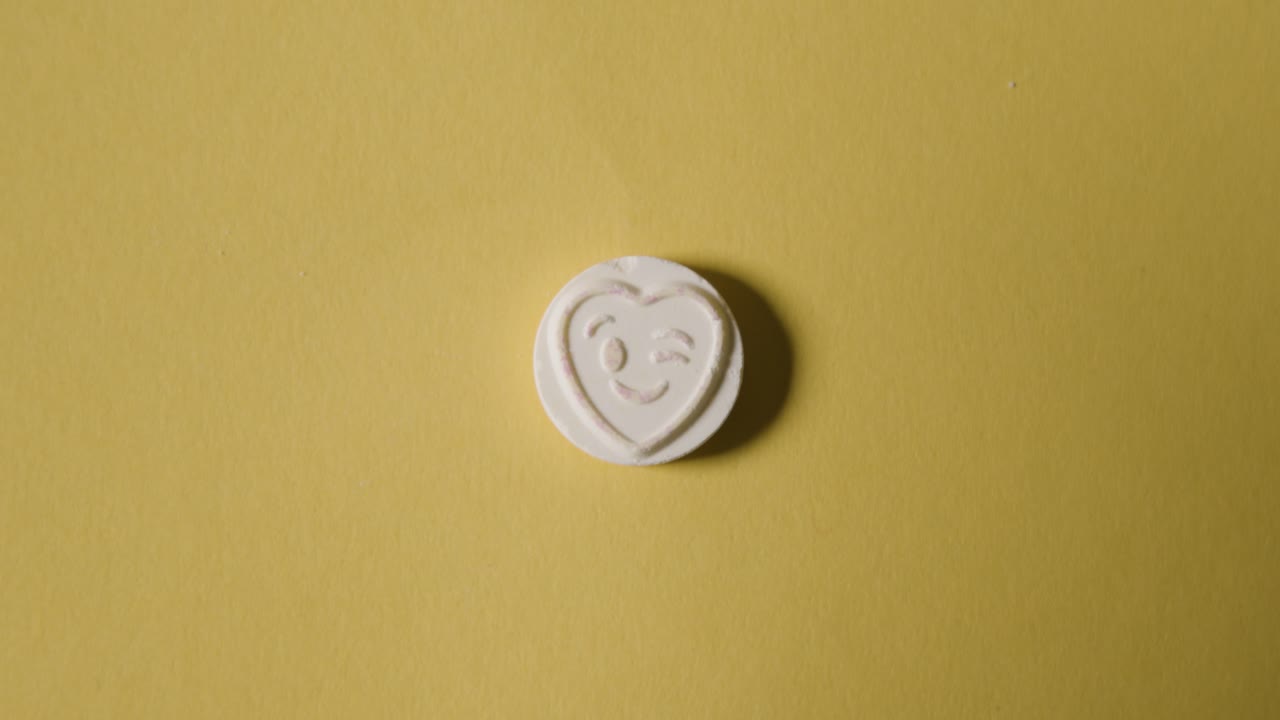 Hand Picking Up Heart Candy With Winking Emoji On Yellow Background