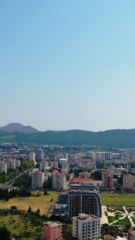 scenic view of the city at the coast of adriatic sea. green mountain ranges at backdrop. sunny day footage from drone. vertical video