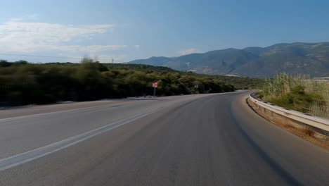 driving on a turkish road running along the sea, with a mountain view in the background