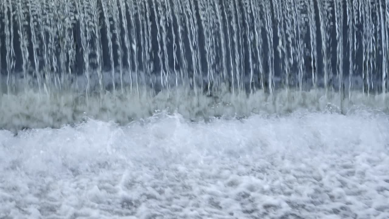 Repeating pattern as water pours over small river weir in whitewater