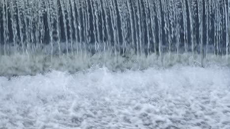 repeating pattern as water pours over small river weir in whitewater