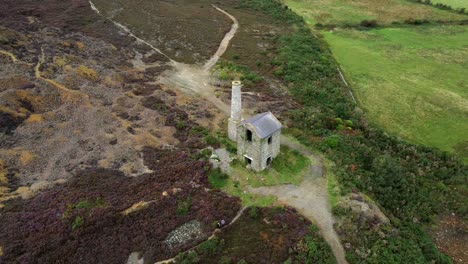 Parys-mountain-abandoned-brick-chimney-copper-mining-mill-stone-ruin-aerial-view-high-descending-reveal