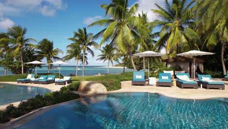 Empty-Pool-and-Poolside-of-Luxury-Tropical-Beachfront-Resort,-Drone-Shot