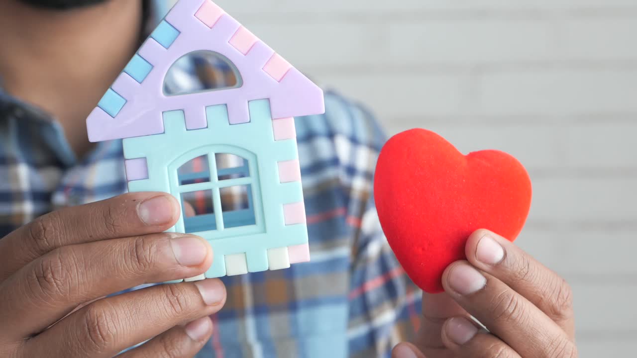 장난감 집과 심장을 들고 있는 사람