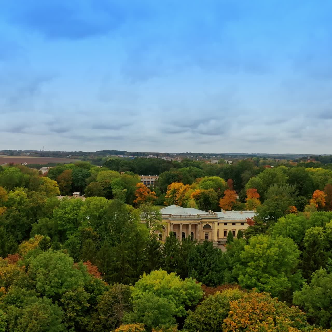High trees park with beautiful palace in the middle. Farmlands at backdrop. Cloudy sky at background. Top view