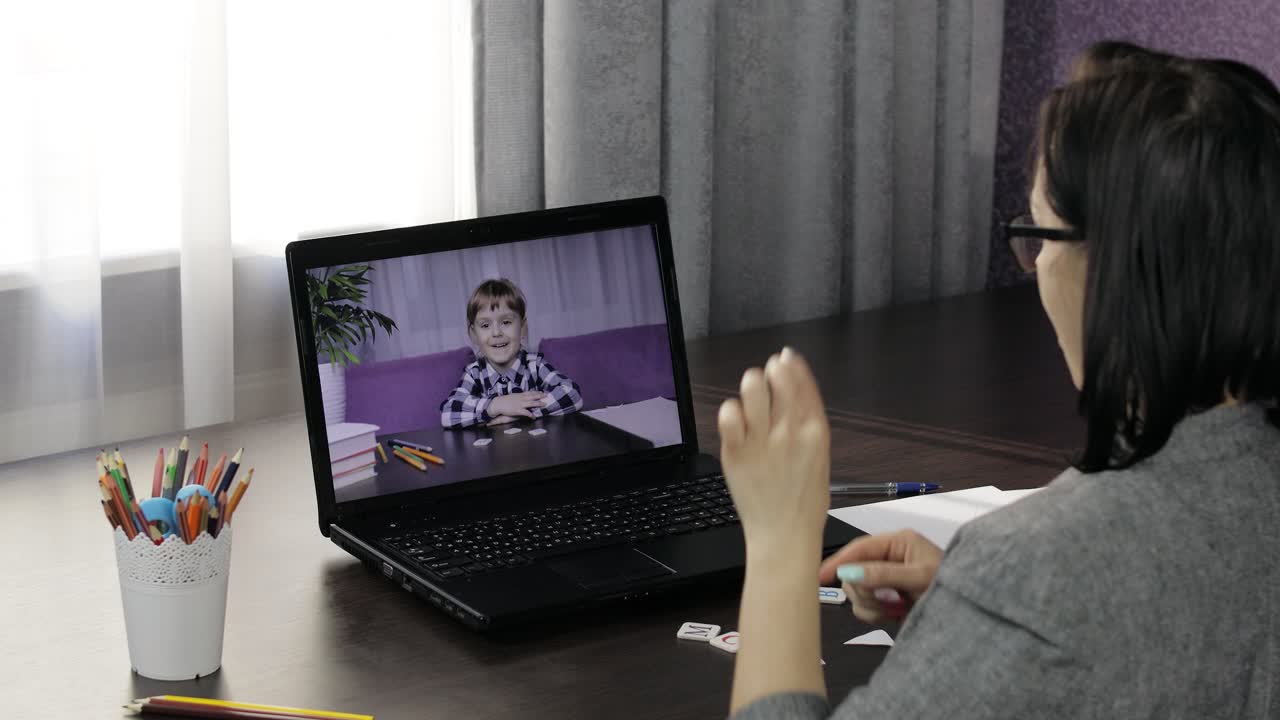 Woman teacher making video call on laptop with little pupil. Distance education