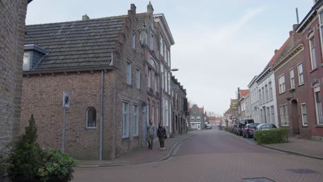 young interracial couple explores old european villages, dutch brick houses, street scene