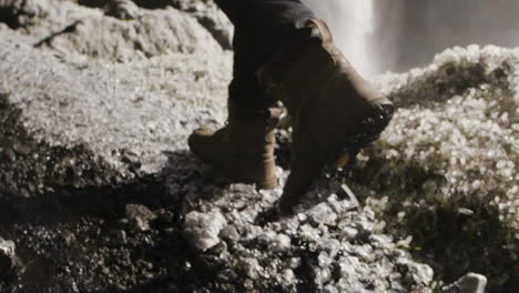 young male traveler walking a frozen path in front of a waterfall slow motion