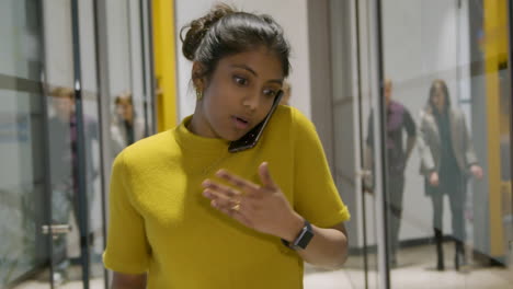 Woman-Talking-On-Smartphone-In-A-Corridor