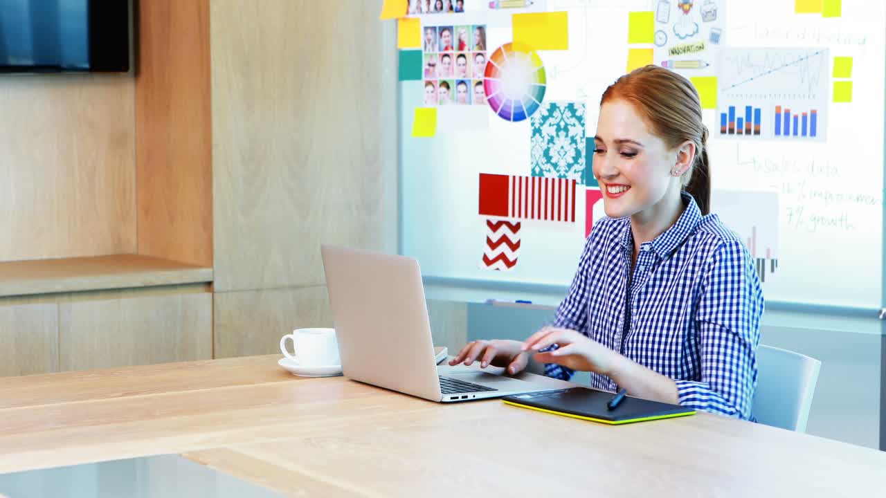 회의실에서 노트북과 그래픽 태블릿을 사용하는 여성 그래픽 디자이너