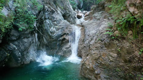 hombre saltando del acantilado a una cascada desde un cañón rocoso, aéreo