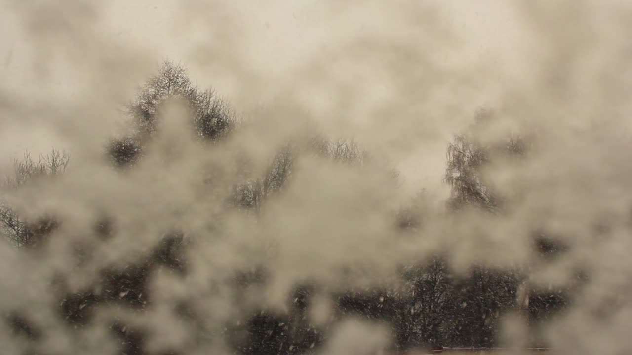 A view from a window in the winter. Outside is snowing.